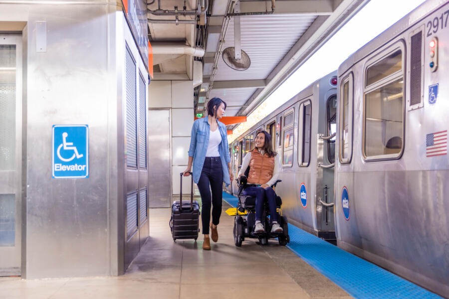 Two CTA passengers in Chicago on a train platform, one is in a wheelchair