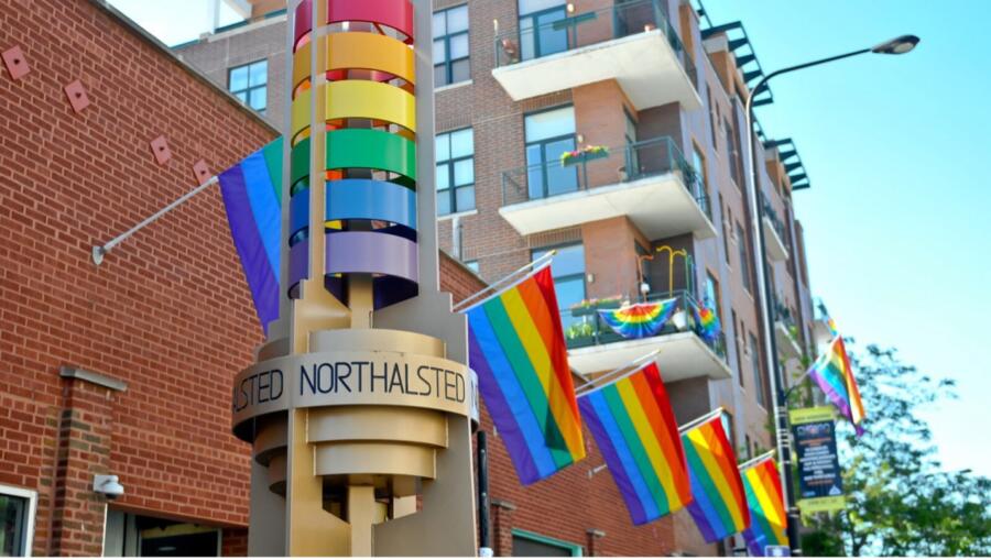 Rainbow Legacy Walk pillar in Northalsted, Chicago’s first official LGBTQ neighborhood, surrounded by pride flags and decorated balconies during Pride Month.